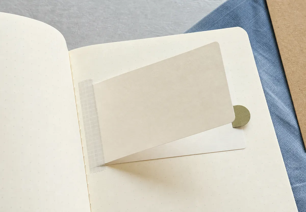 Close view of a journal page with a narrow paper hinge, partially open memo flap, and pull tab
