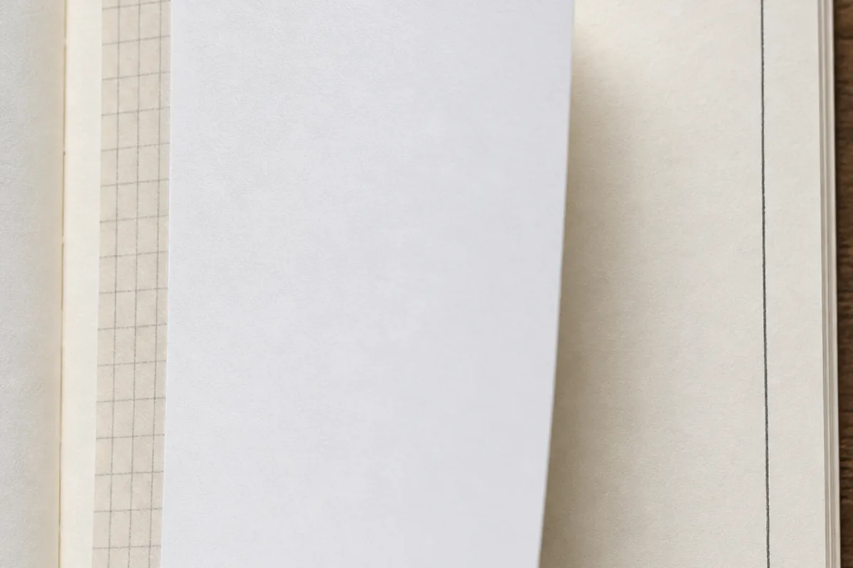 Close-up of a plain memo tip-in attached to a journal page with one taped hinge edge